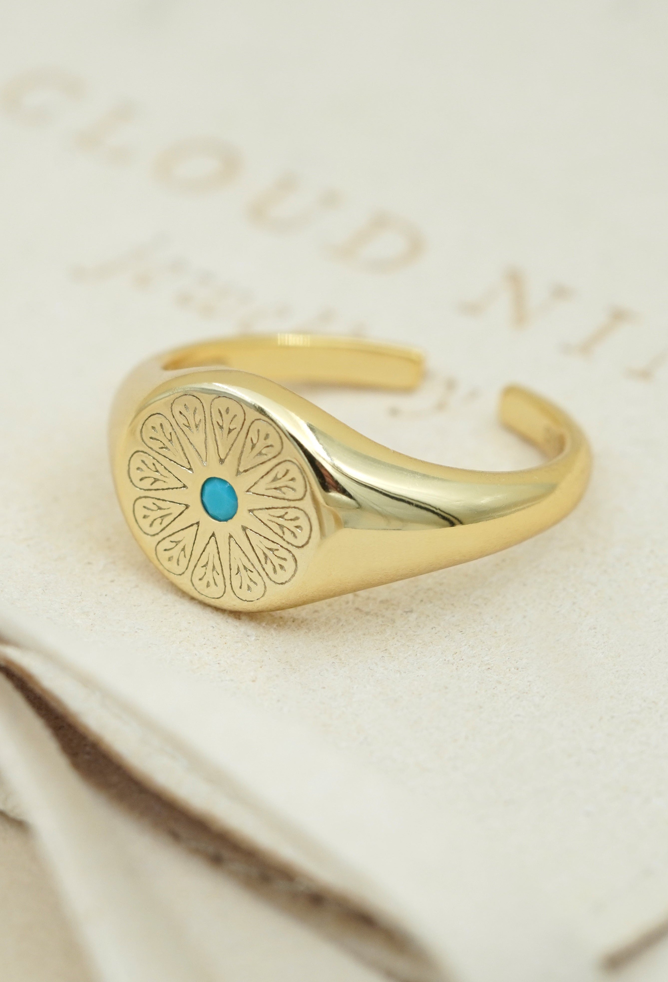 Gold December Turquoise Signet Ring on cream fabric