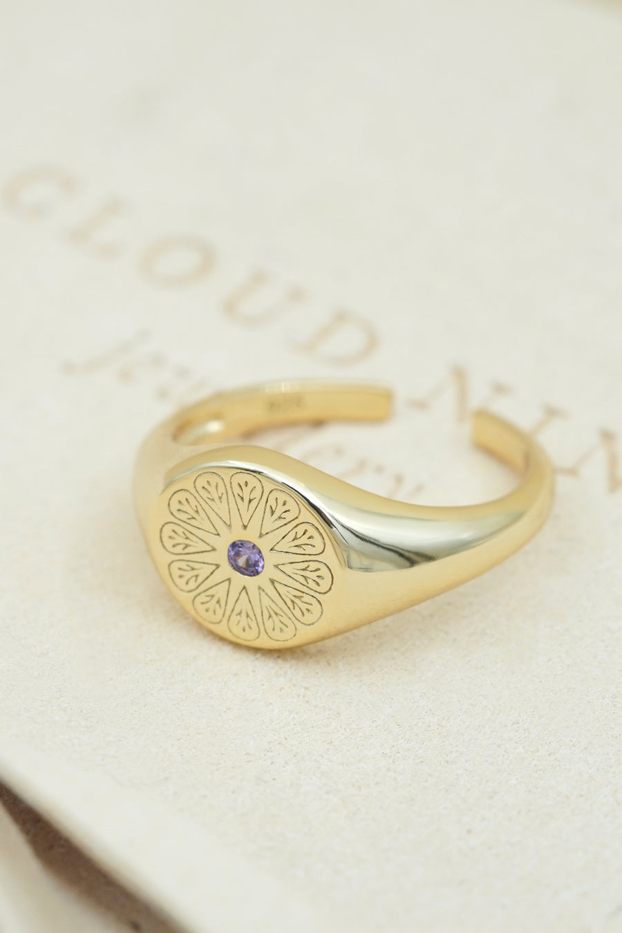 Gold February Amethyst Birthstone Ring on cream fabric