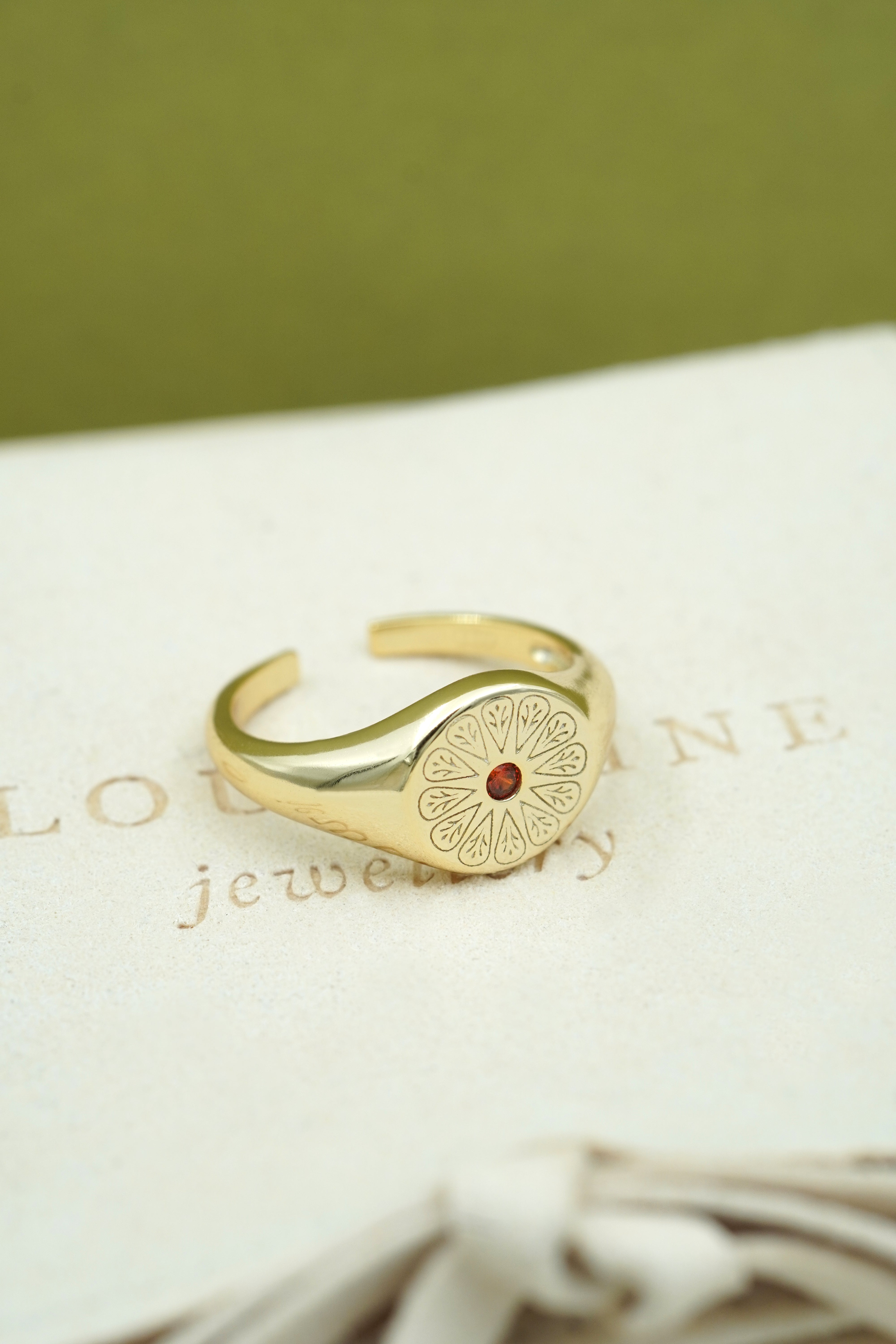 Gold January Garnet Birthstone Ring on cream fabric