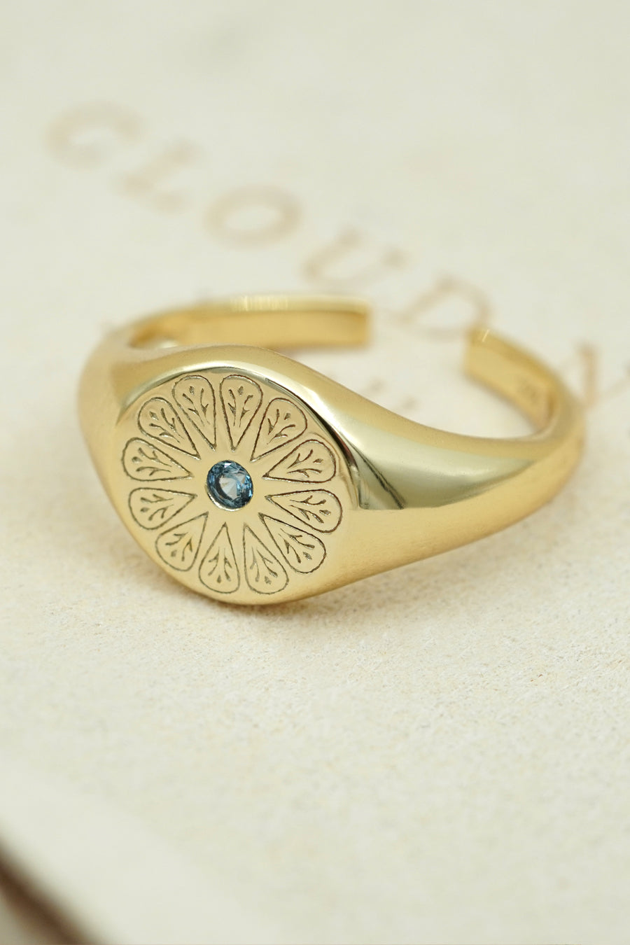 March Aquamarine Gold Signet Birthstone Ring on cream fabric