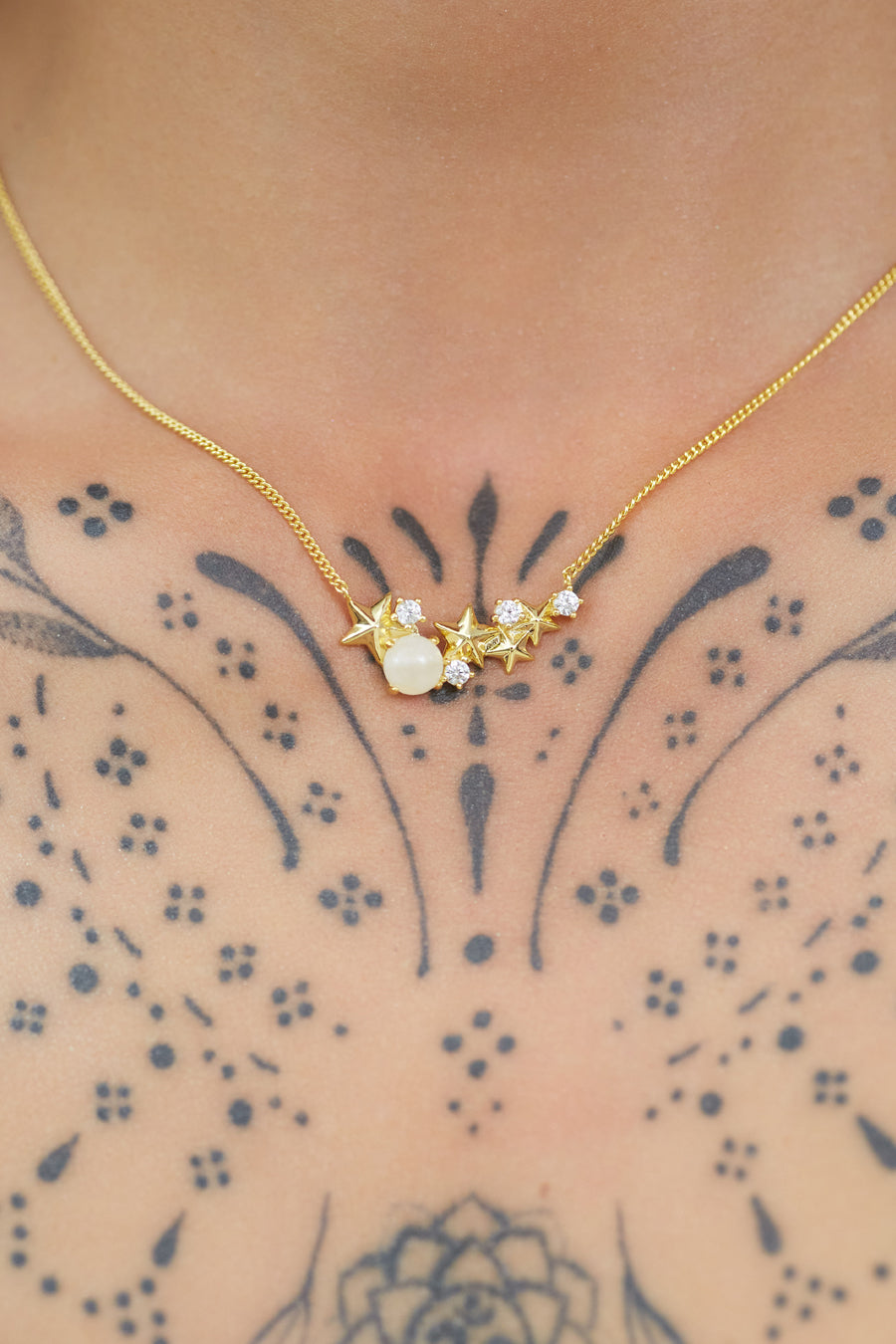 Gold Matariki Necklace worn on tattooed neck