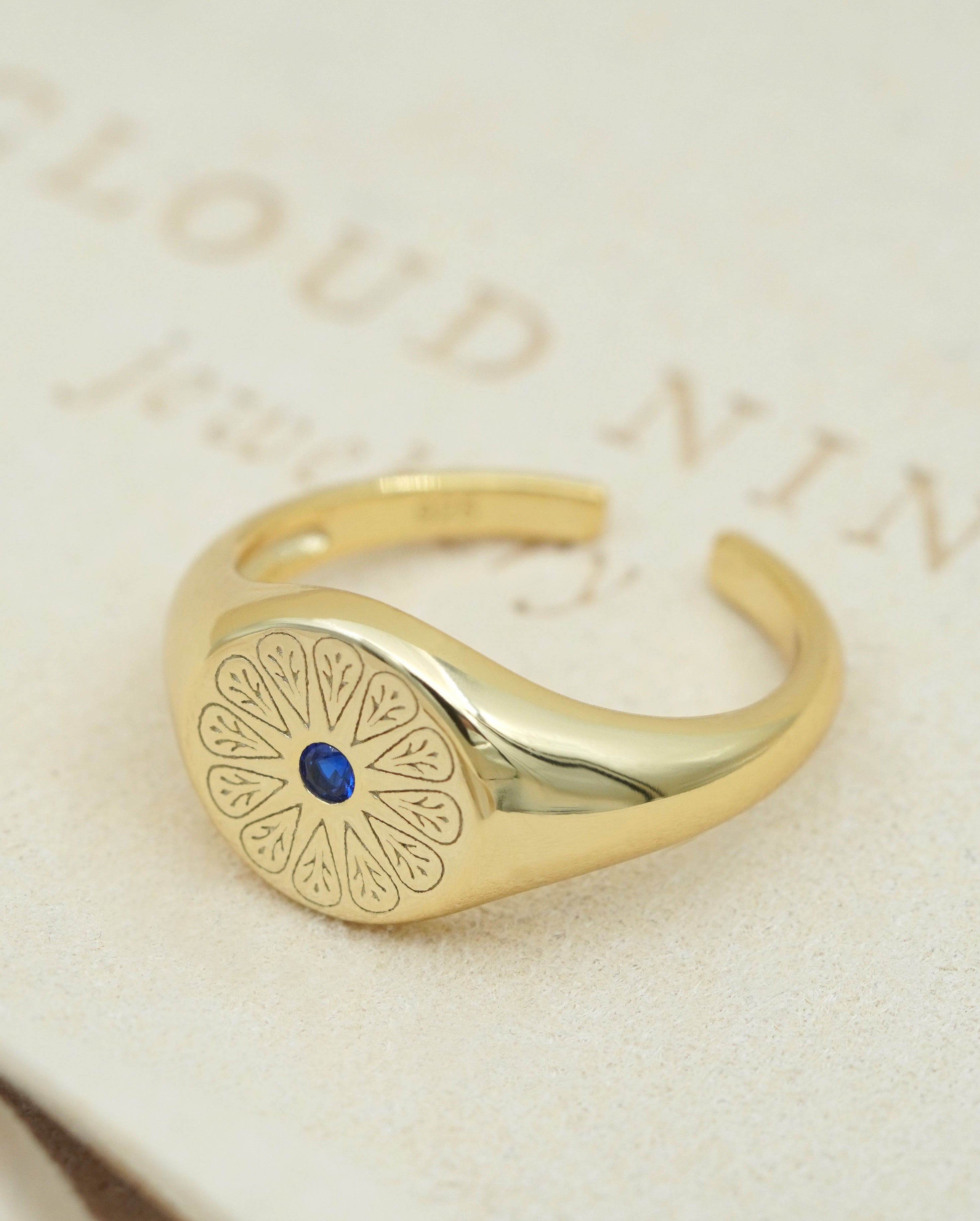 Gold September Sapphire Signet Birthstone Ring on Cream fabric